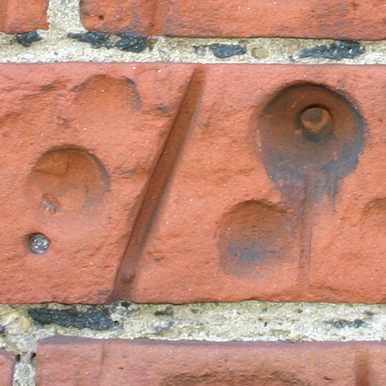 Holes bored into brickwork adjacent to a bus stop